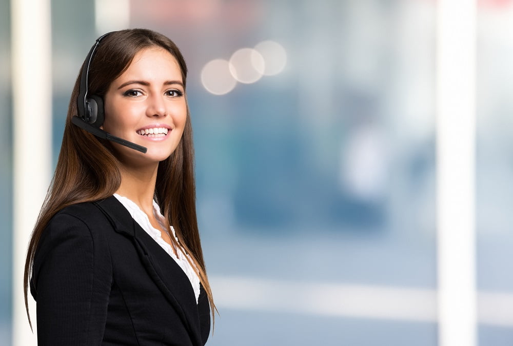 Mujer sonríe con audífono/  trabaja en atención al cliente