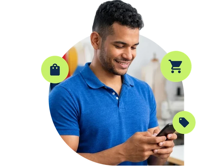 Vendedor sorridente olhando o celular em uma loja de roupas.